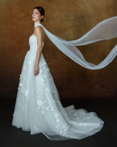 Woman in a white wedding dress with a long train against a brown background