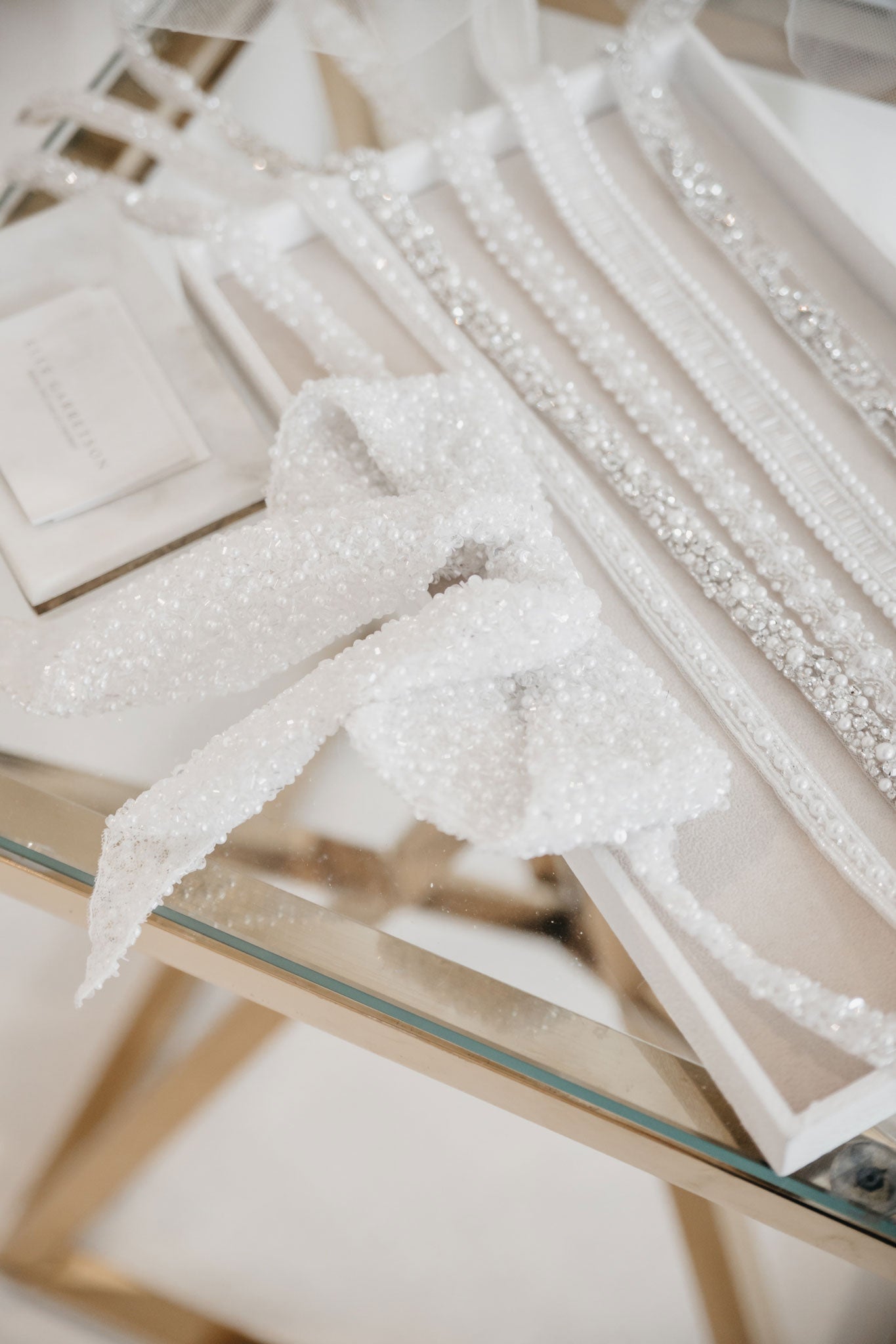 Glass top wooden table with pearl beaded ribbons and bridal accessories exhibition at the new york bridal market